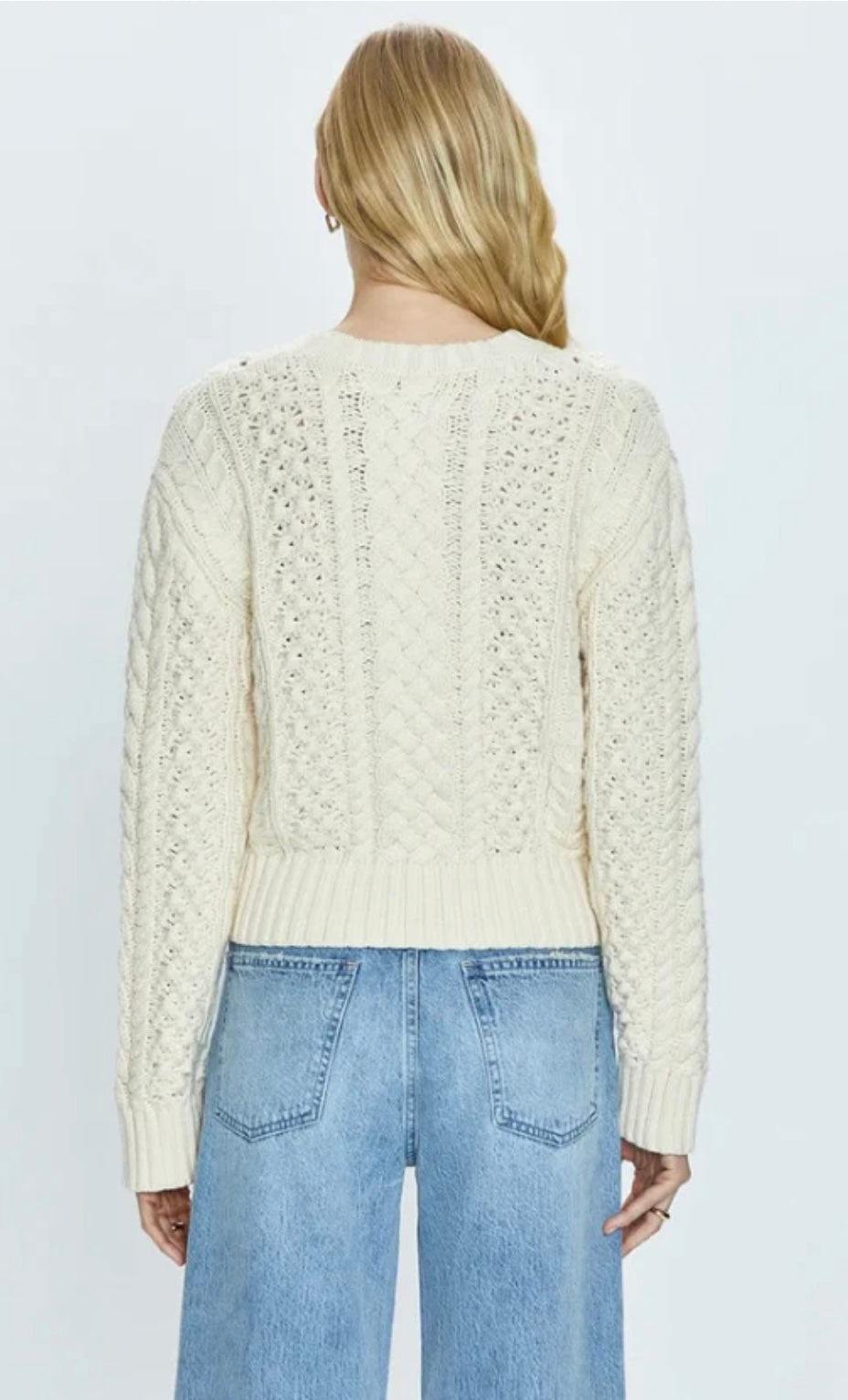 back view of woman wearing Quinn Ivory cable knit fisherman sweater with shrunken silhouette and light blue denim jeans