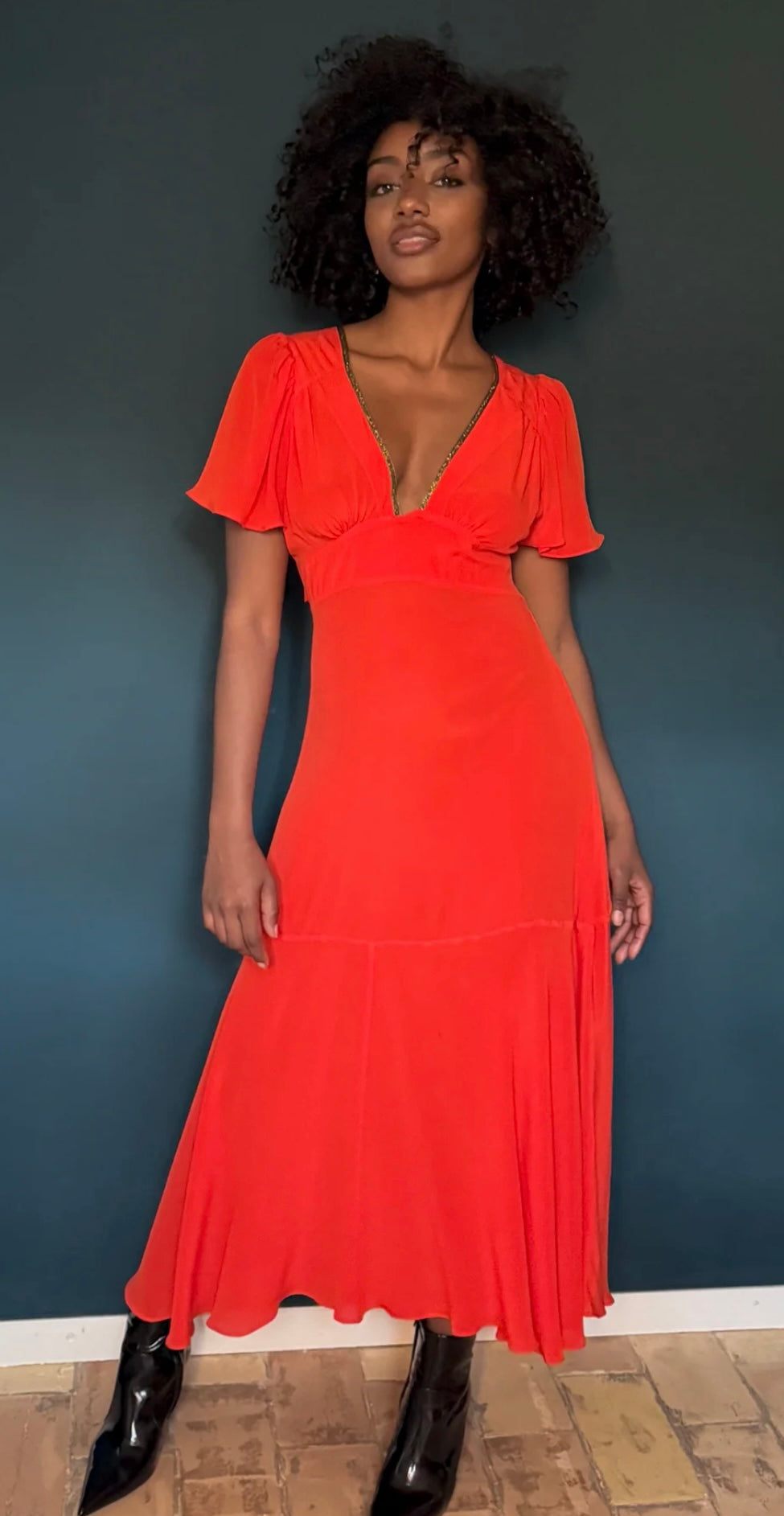 The Iris Fire Red dress by HANSINE LONDON worn by model against dark background