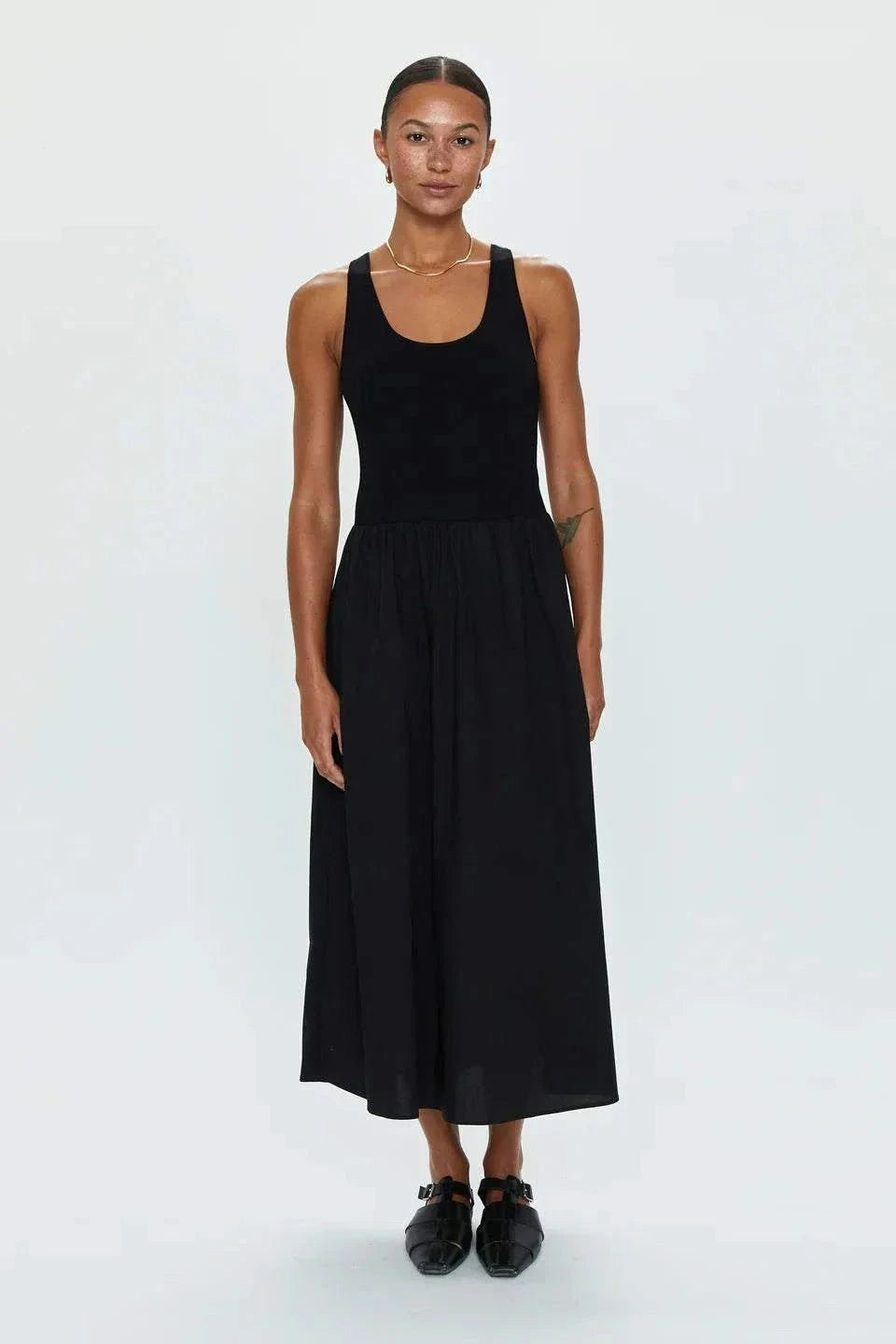 Woman wearing black Faye Tank Dress with sleeveless design and relaxed skirt