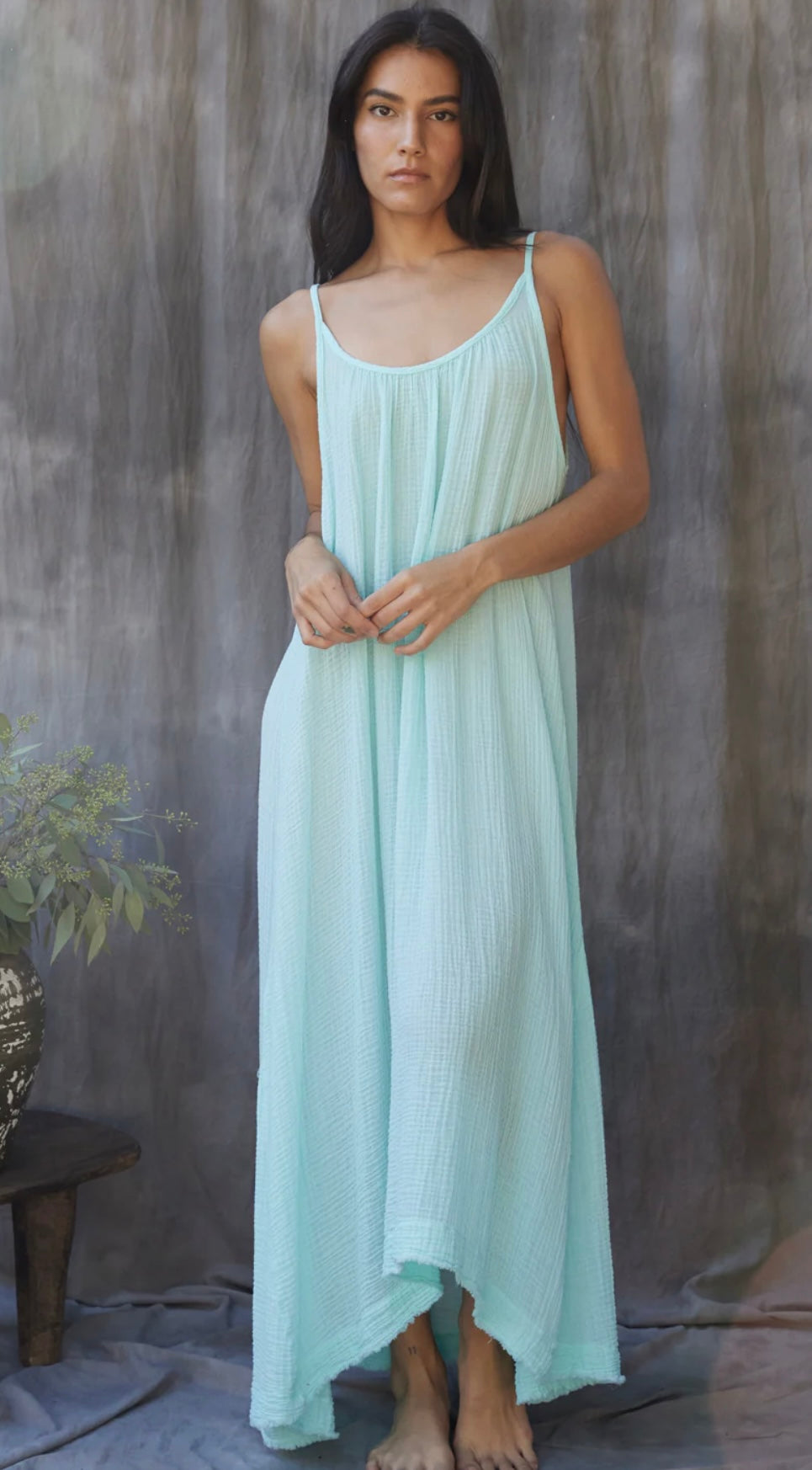 Woman wearing light blue Tulum Dress Ocean with thin straps standing against a textured backdrop
