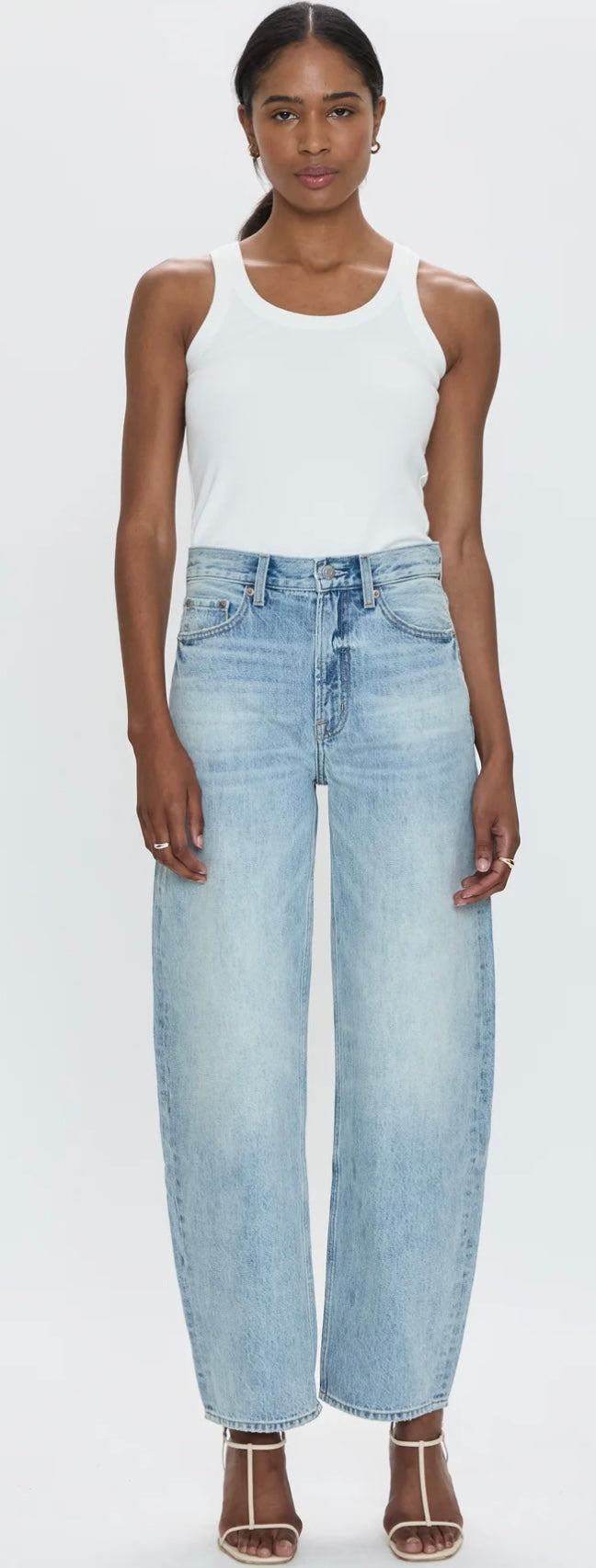 woman wearing Wes High Rise light blue barrel jeans and white tank top standing against white background