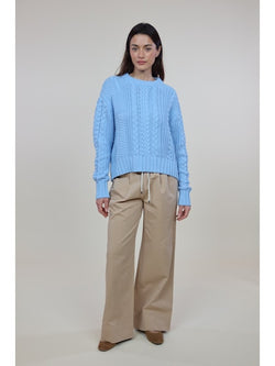 Woman wearing light blue cable knit Cora Sweater with beige wide-leg pants