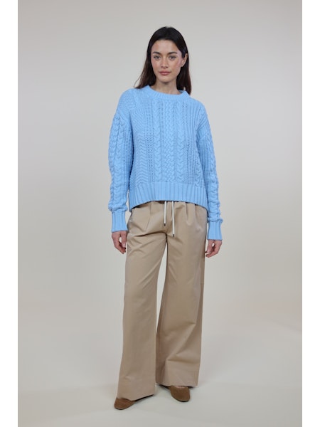 Woman wearing light blue cable knit Cora Sweater with beige wide-leg pants