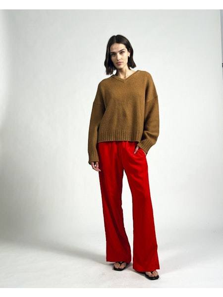 Woman wearing red high-waisted Monaco pants with elastic waistband and brown sweater