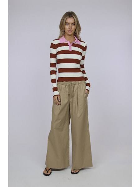 Woman wearing The Debra Top striped long sleeve polo with wide-leg beige pants