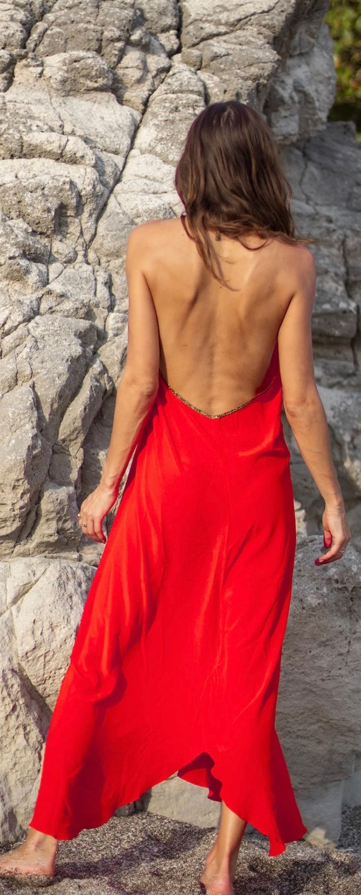 woman wearing The Rhodes Fire Red dress by HANSINE LONDON standing on rocks with back exposed