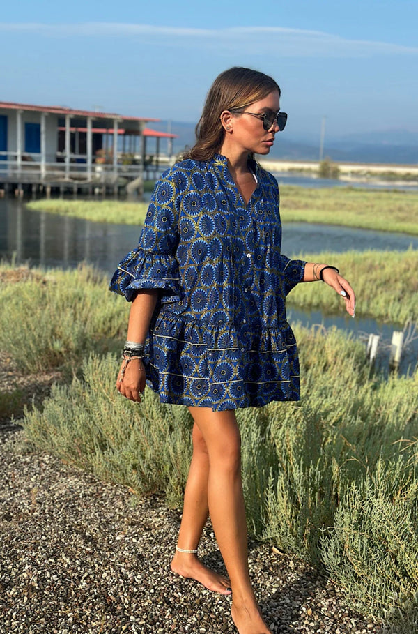 Woman wearing a blue patterned boubou dress standing outdoors near water