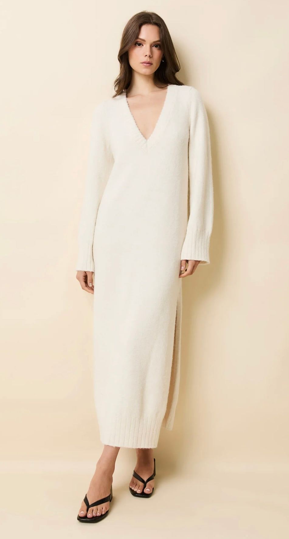 Woman wearing The Edith Dress Brulé SOLID&STRIPED white v-neck long sleeve maxi dress with side slits and ribbed detailing