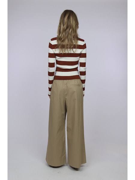 Back view of model wearing The Debra Top striped long sleeve shirt with wide-leg beige pants