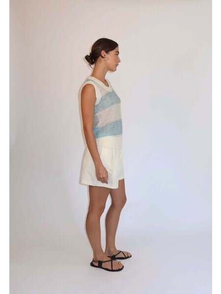 Woman wearing The Zola Tank in blue pastel and ércu stripes with white shorts and black sandals