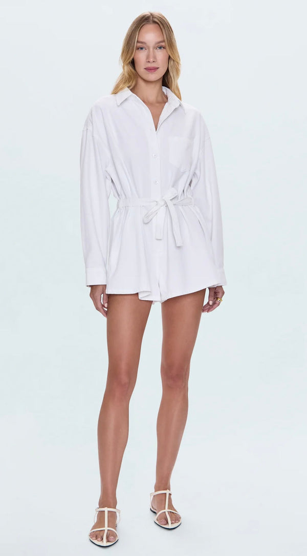 Woman wearing white Vance Denim Romper with long sleeves and waist tie