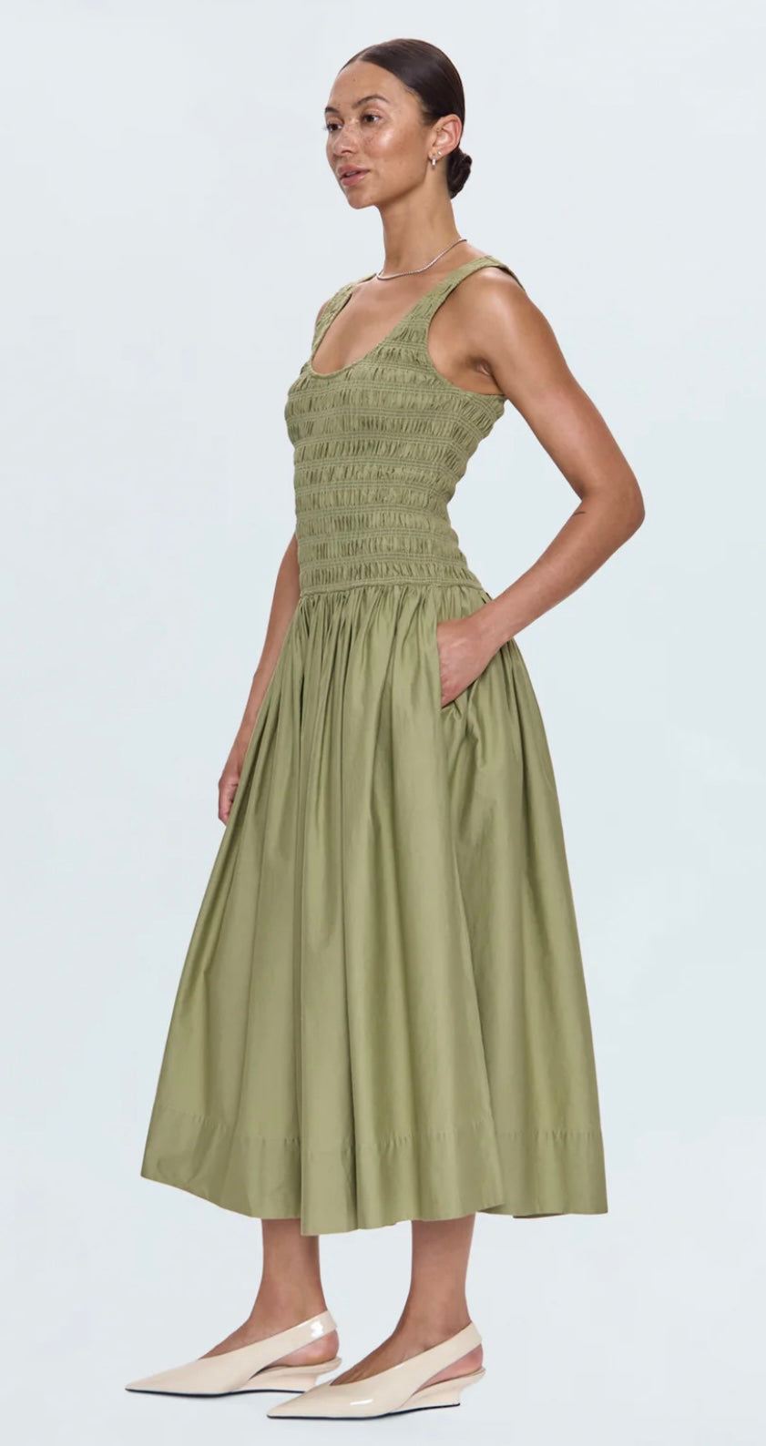 Woman wearing sage green Alessia Dress with ruched midi skirt and side pockets