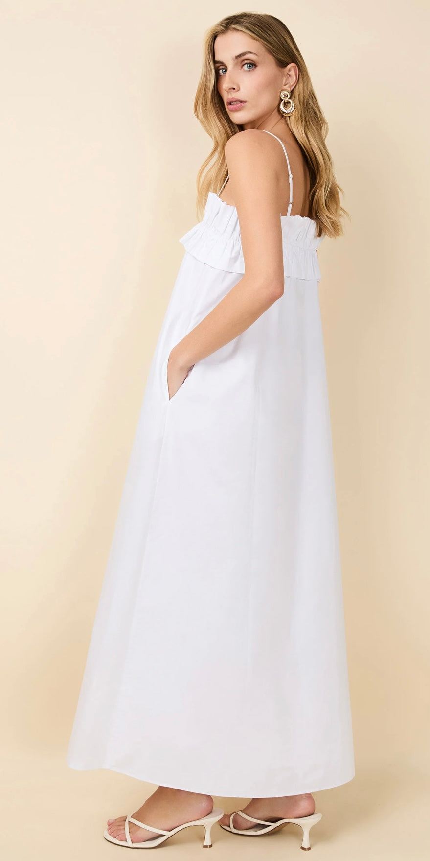 Woman wearing The Sophie white maxi dress by SOLID&STRIPED with thin straps and pockets