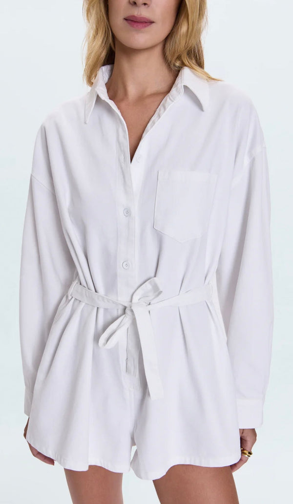 Woman wearing Vance Denim Romper in optic white with long sleeves and front tie belt