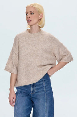 Woman wearing oatmeal Shiloh Sweater with short sleeves and relaxed fit paired with blue denim jeans