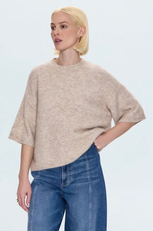 Woman wearing oatmeal Shiloh Sweater with short sleeves and relaxed fit paired with blue denim jeans
