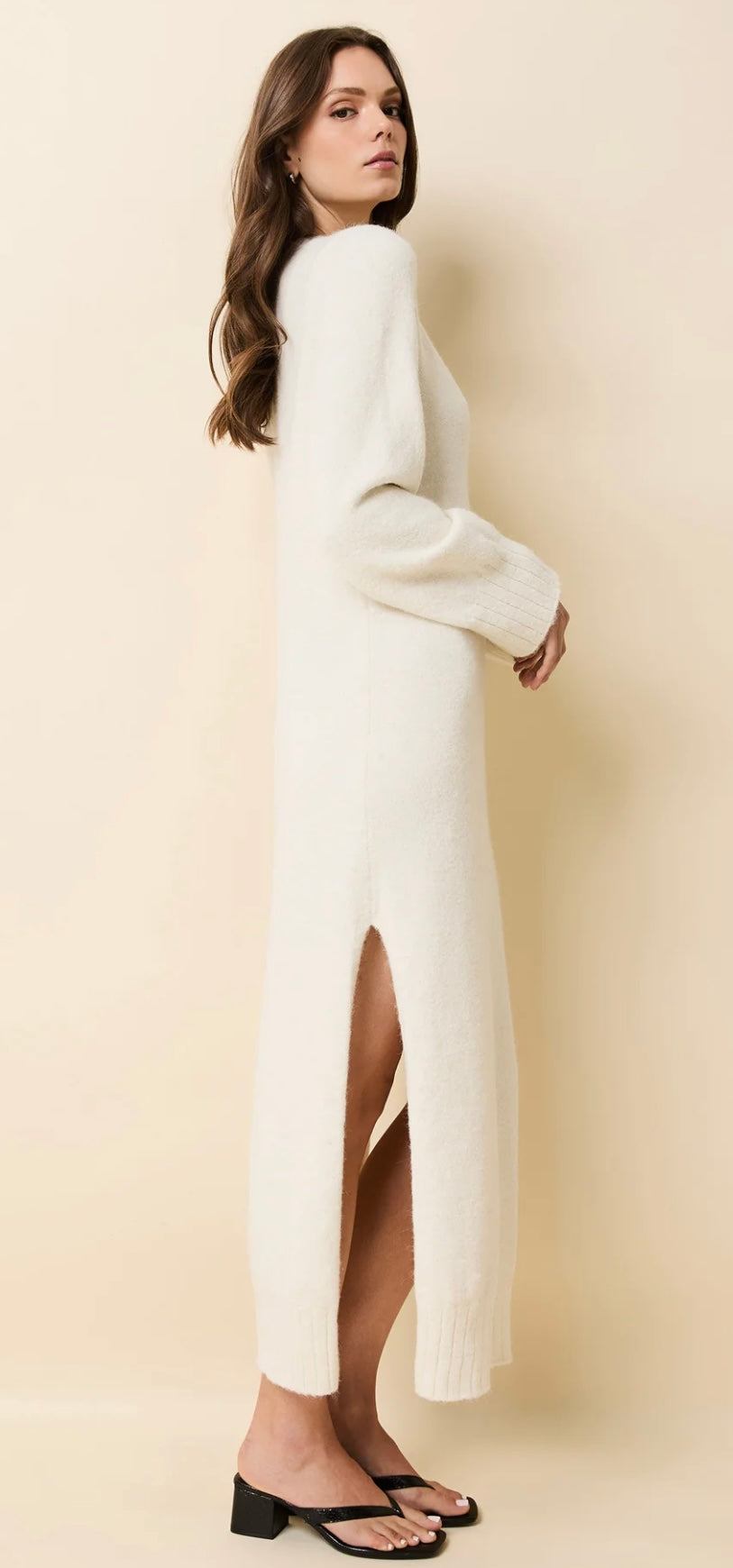 Woman wearing The Edith Dress Brulé SOLID&STRIPED white knit maxi dress with v-neck, flared sleeves, and side slit