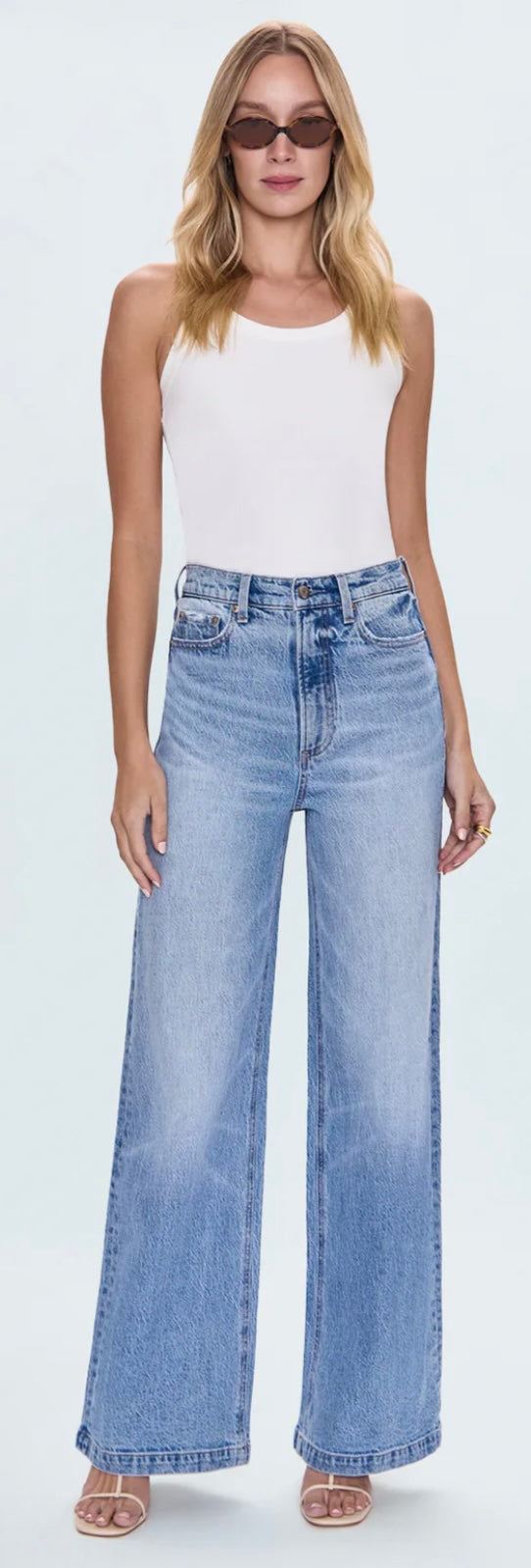 The Lana Wide Leg denim jeans in light wash with high-rise waist and relaxed full-length silhouette worn by a woman in white tank top and sunglasses
