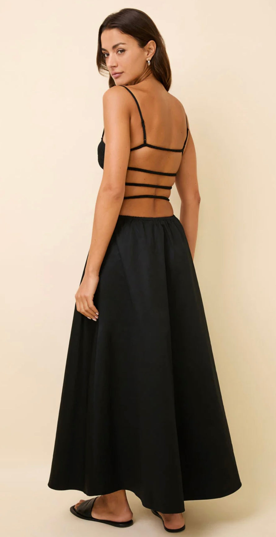 Black Delta Dress with smocked bodice, adjustable straps, exposed elastic back, and relaxed midi skirt with pockets.