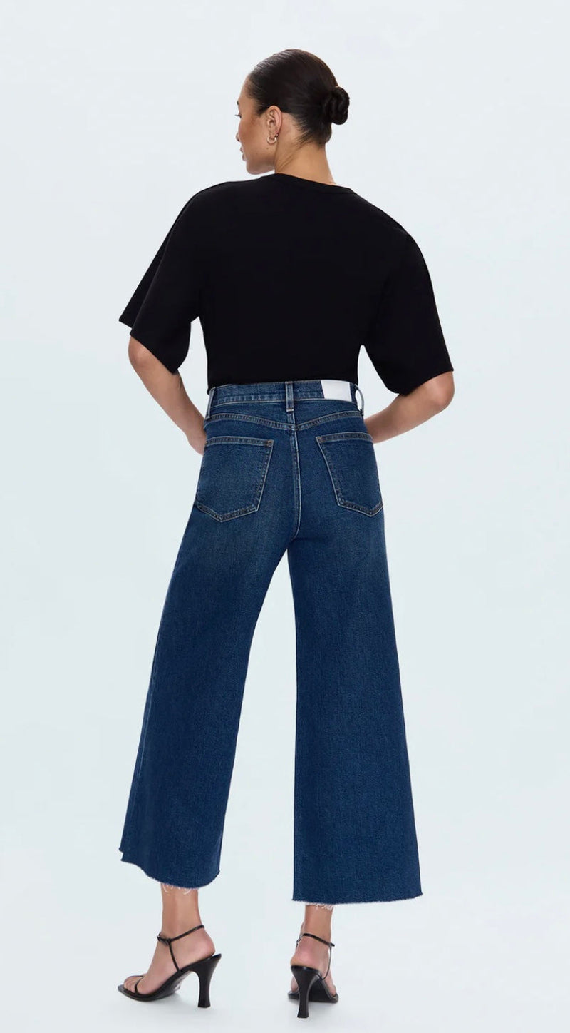 Back view of a woman wearing Lana Cropped high-rise wide-leg dark wash denim jeans with raw hem and relaxed fit