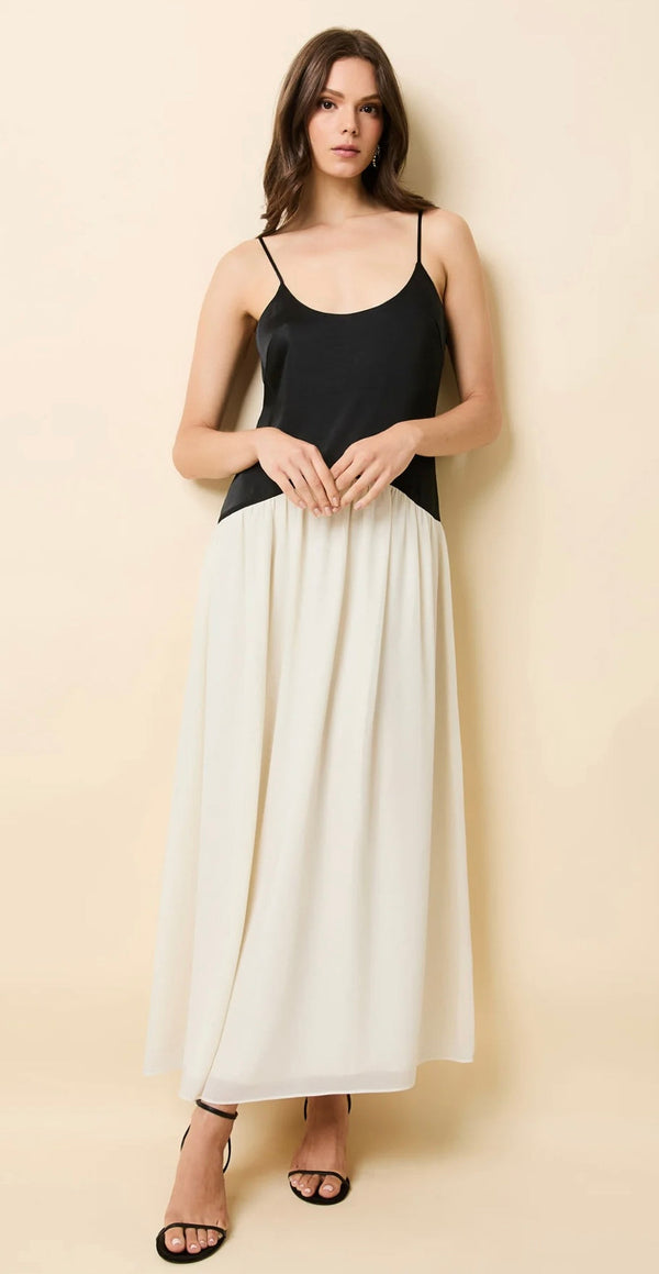 Woman wearing The Tallula Noir black spaghetti strap top paired with a white flowing skirt against a beige background