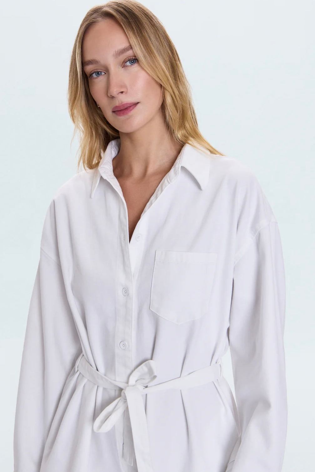 Woman wearing white Vance Denim Romper with front buttons and waist tie