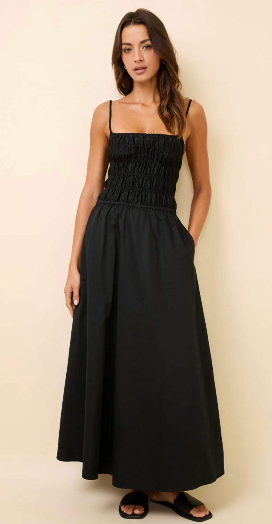 Black Delta Dress midi with smocked bodice, adjustable straps, pockets, and relaxed skirt.