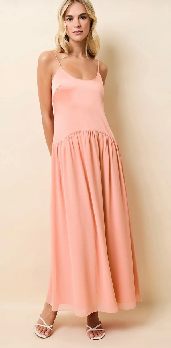 Woman wearing a peach Talulla Pechykeen sleeveless maxi dress with thin straps and a gathered skirt.