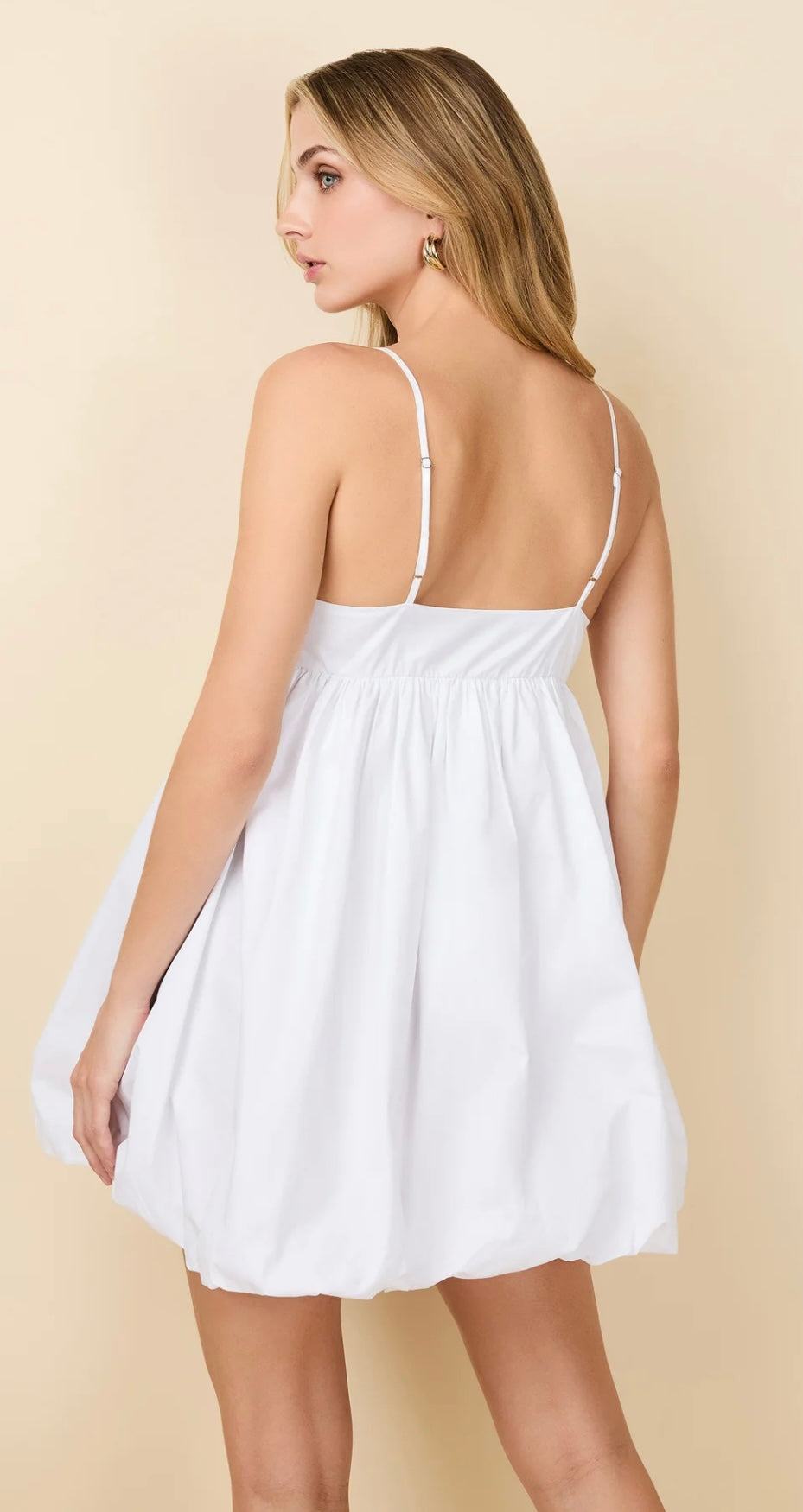 Back view of woman wearing The Charlotte Optic White baby doll dress with voluminous skirt and empire waist
