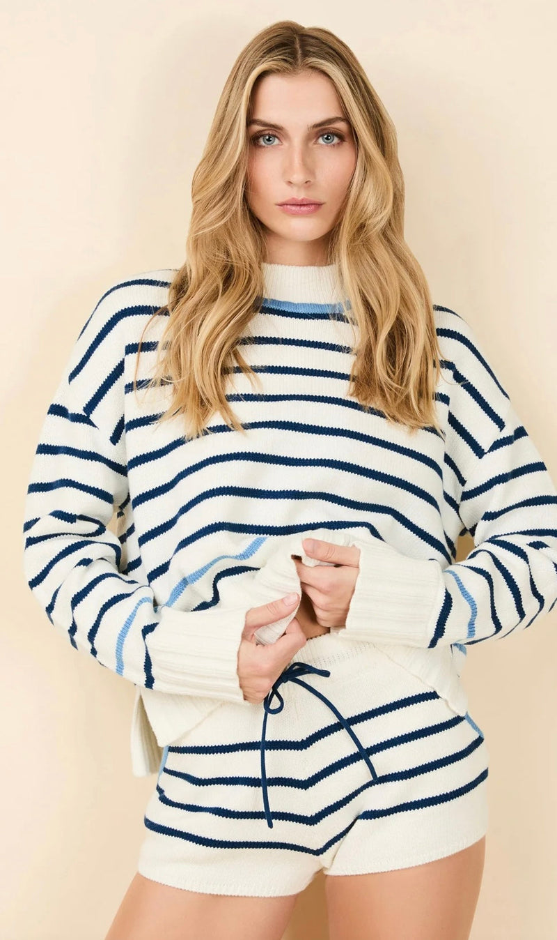 Woman wearing The Maxine Sweater with blue stripes, wide ribbed cuffs, and side slits in a cotton-wool blend