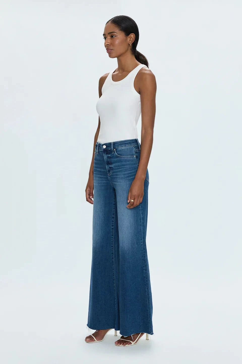 Woman wearing Izzy Jeans Study PISTOLA high-rise slim straight-leg denim jeans with a white tank top and heels