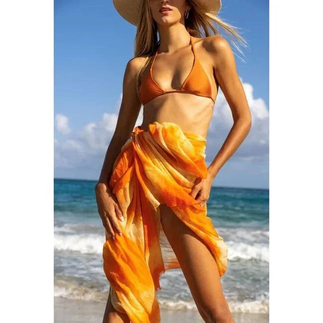 Woman wearing fiery sunset cashmere dip dye pareo on beach with ocean background