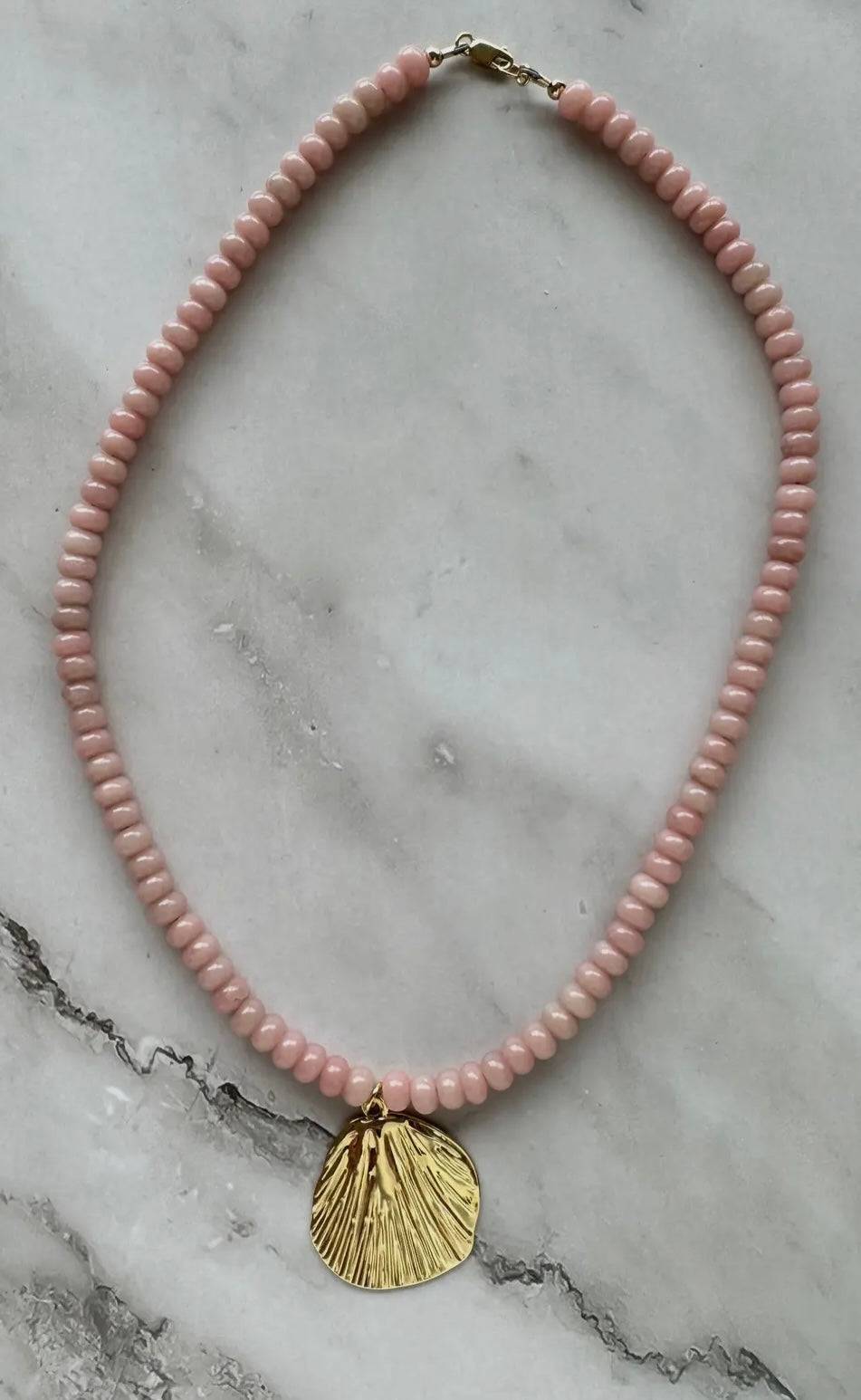 Pink Shell Necklace with gold shell pendant and pink beads on marble background