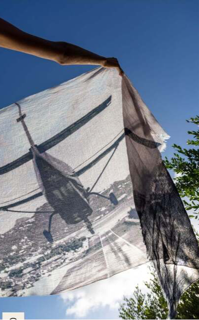 Cashmere St Barth Landing scarf with airplane print held against blue sky