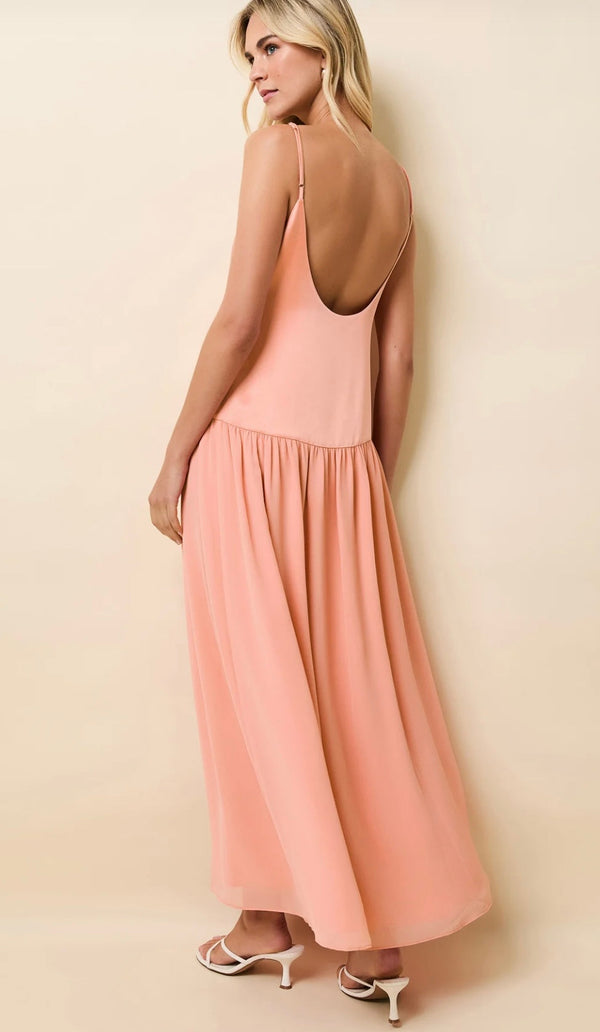 Woman wearing a peach Talulla Pechykeen dress with thin straps and a low back design.