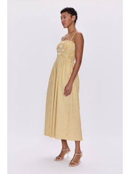 Woman wearing Bianca Beach Sand Stripe Dress by PISTOLA DENIM, yellow striped midi dress with thin straps and flowy design