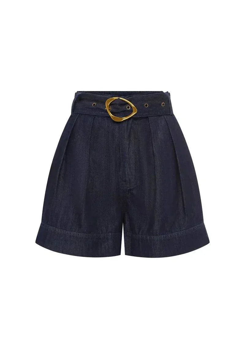 Ana Denim Shorts in indigo with gold belt buckle, pleated A-line shape, mid-thigh length, and patch pockets