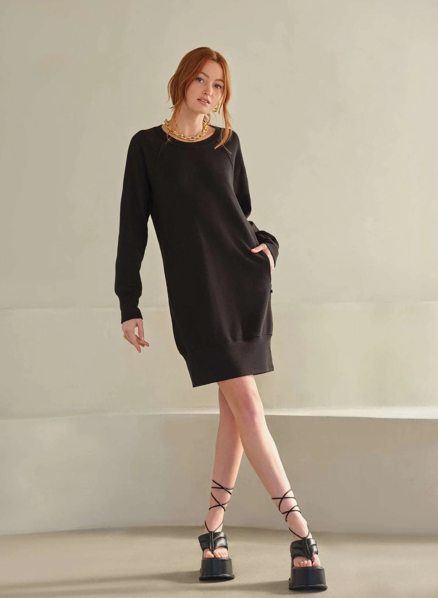 Woman wearing black MiniLux Pocket Dress with side pocket detail and long sleeves