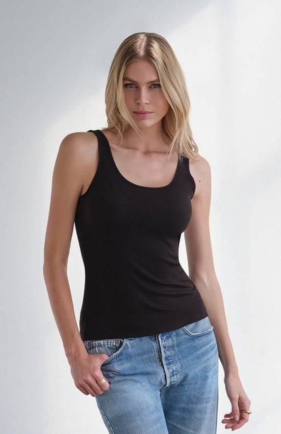Woman wearing black MiniRib Tank with blue jeans standing against white background