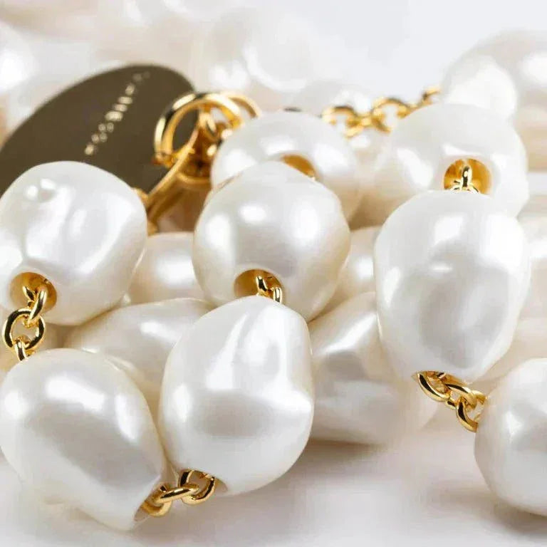 Close-up of organic pearl long necklace with gold chain links and circular pendant by Vanessa Baroni