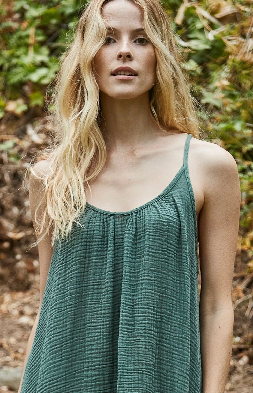 Woman wearing a moss green Tulum Maxi Dress made of 100% organic cotton gauze with a low back and raw edge hem in an outdoor natural setting