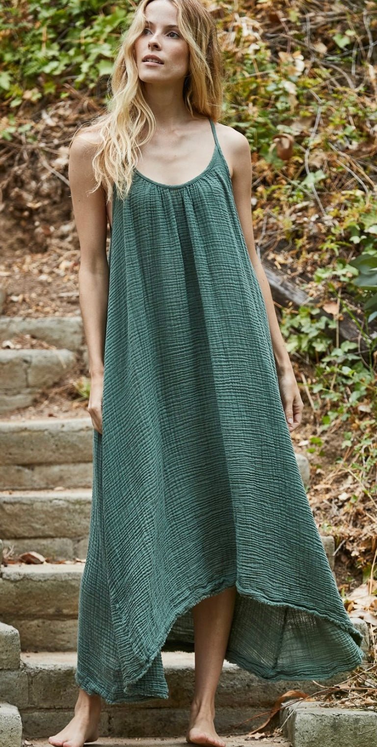 Woman wearing moss green Tulum Maxi Dress by 9SEED made of organic cotton gauze with raw edge hem outdoors.